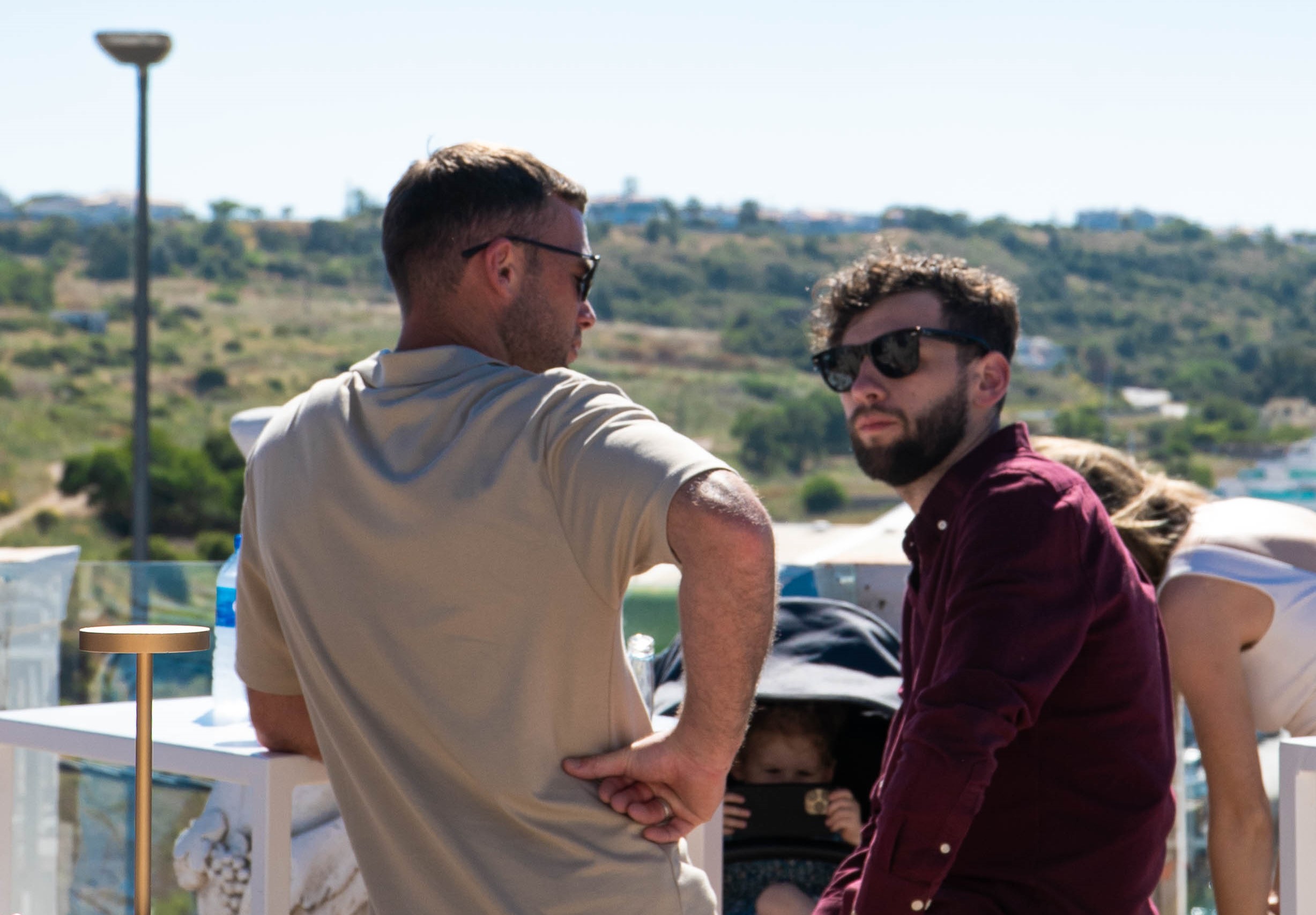 Two men standing on a balcony with a baby in a stroller