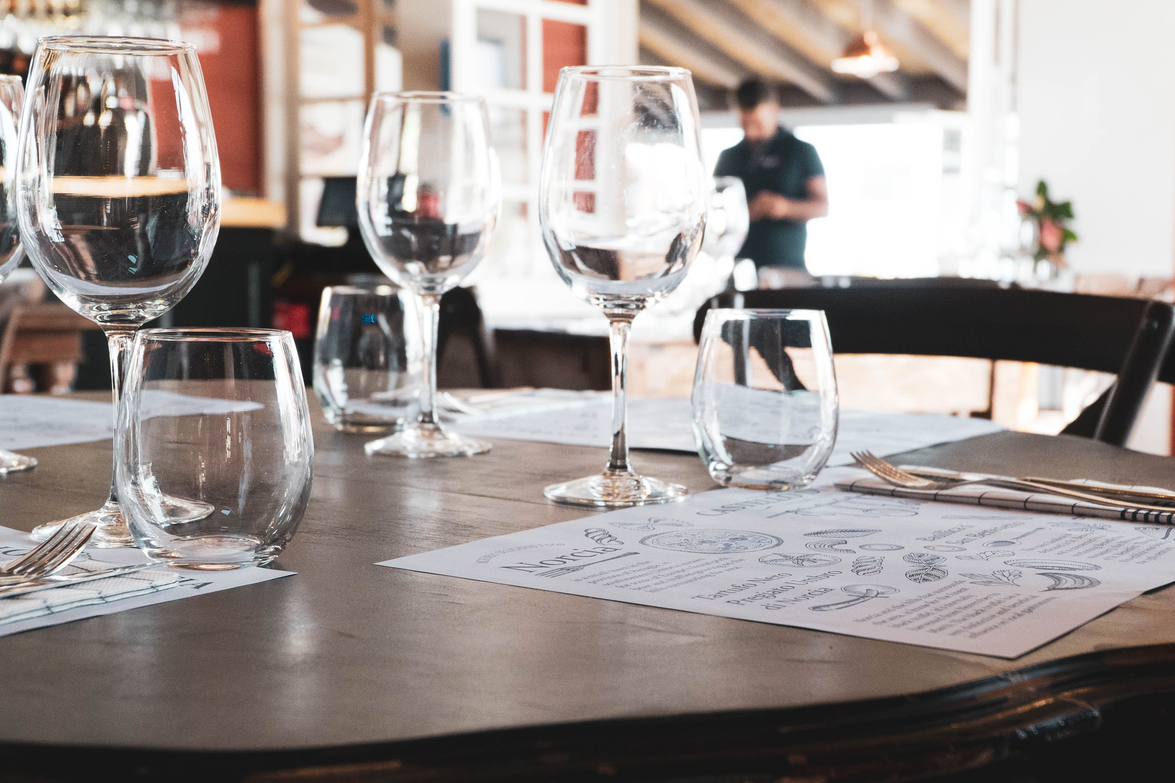 A wooden table with wine glasses on it.